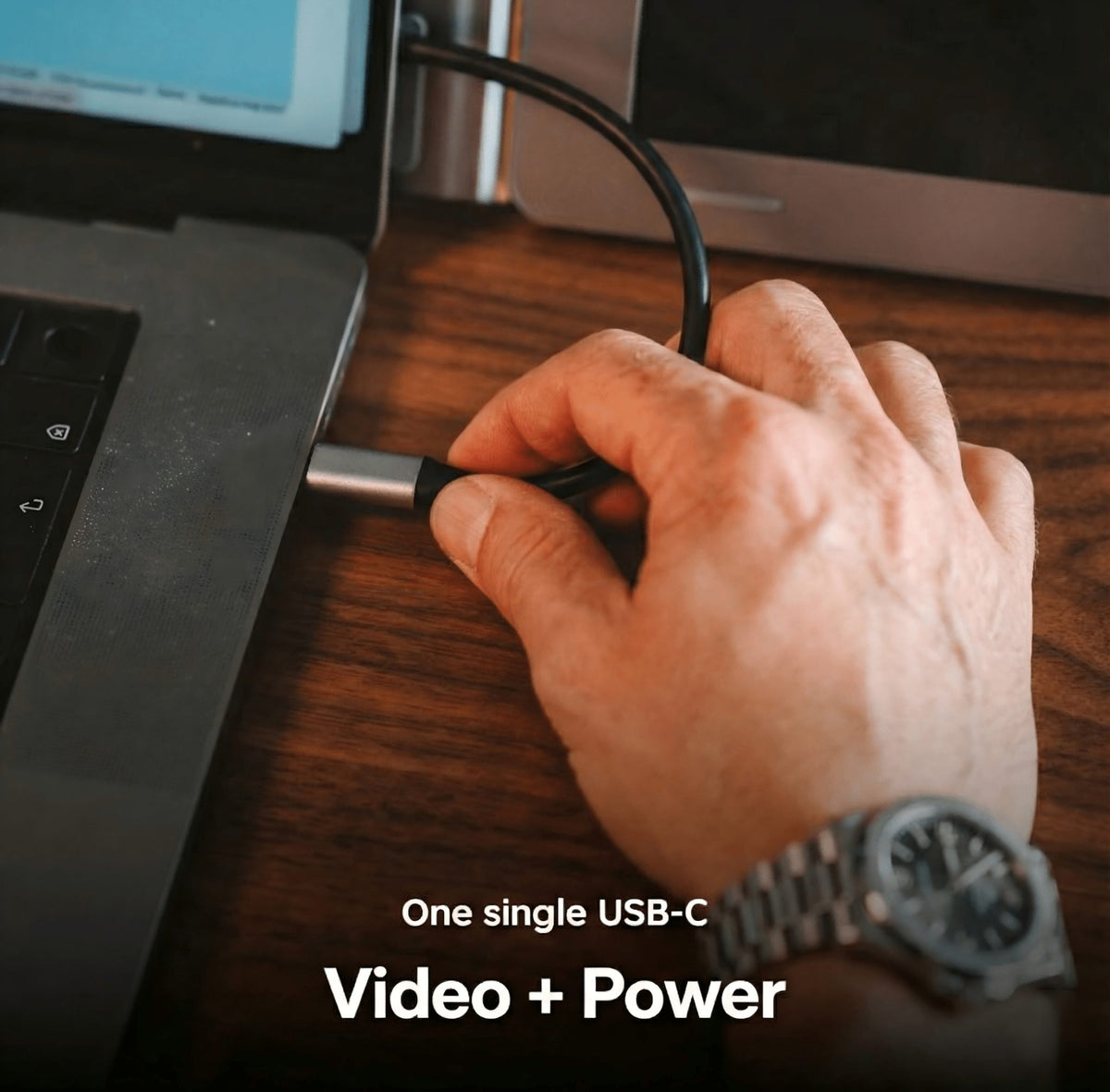 Hand plugging a USB-C cable into a laptop beside a screen extender.